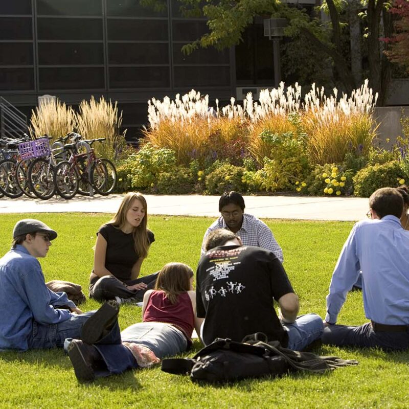 Students and professor sitting in a circle on the grass